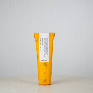 Yellow and white hair product tube with 'davines' branding on a light gray background