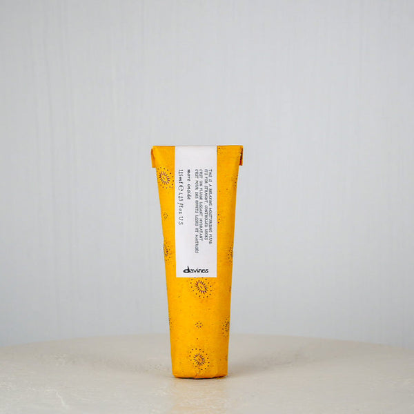 Yellow and white hair product tube with 'davines' branding on a light gray background