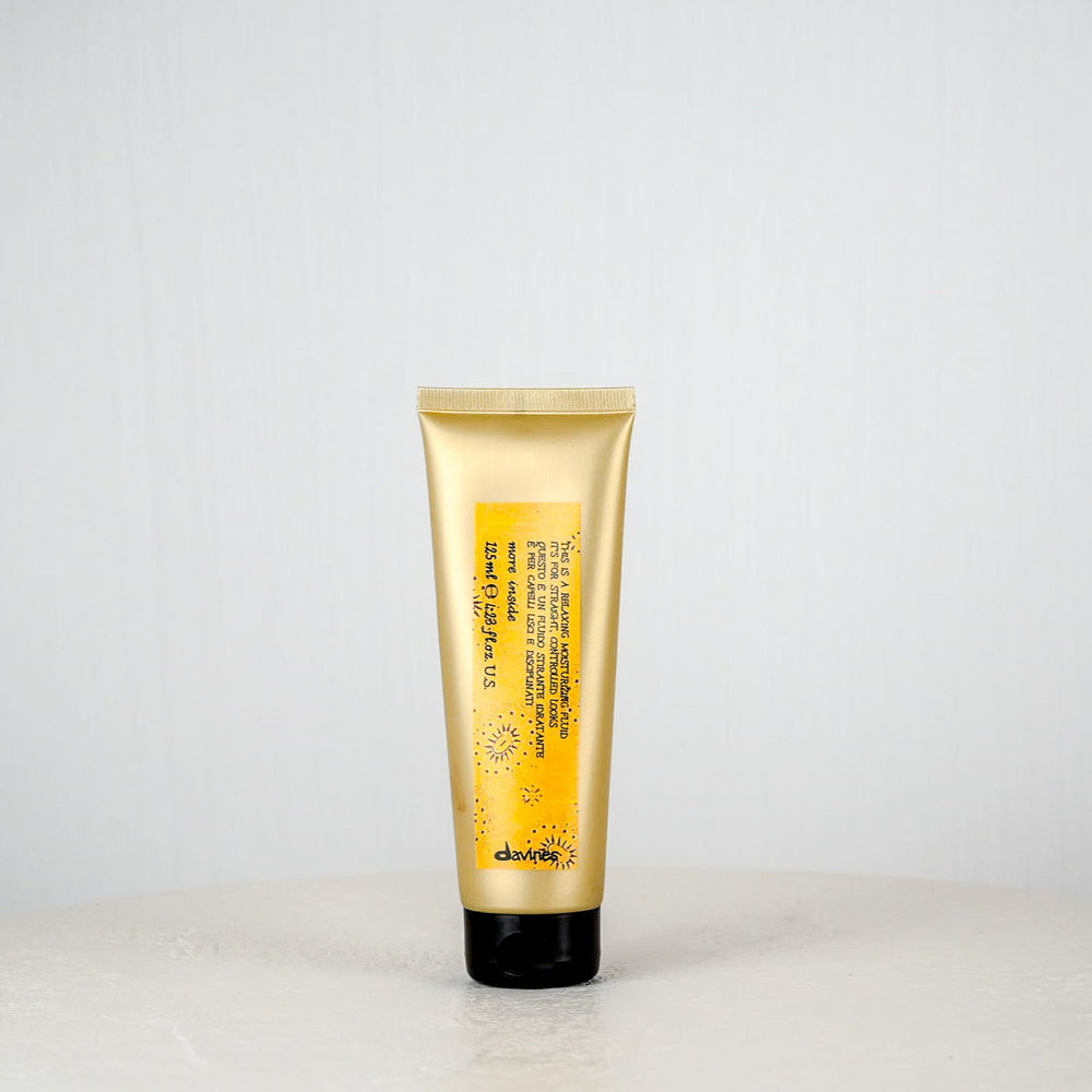 Yellow and white hair product tube with 'davines' branding on a light gray background