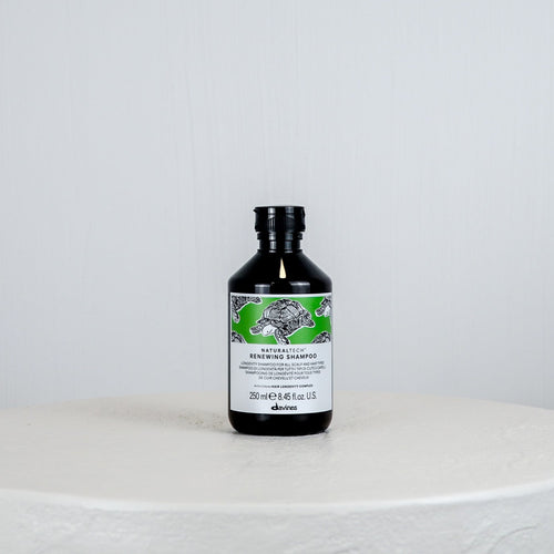 Bottle of Davines shampoo on a white surface with a light gray background