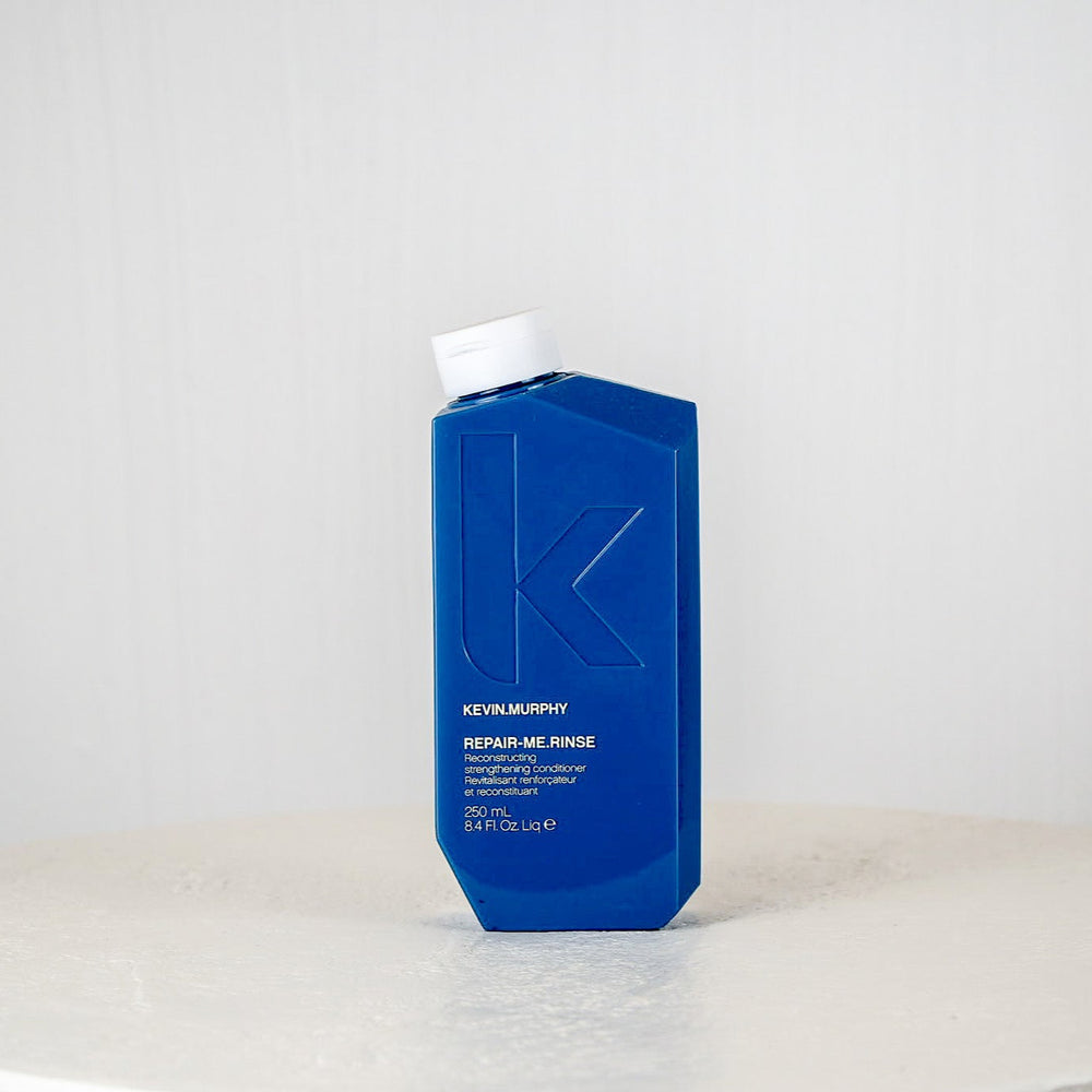 Blue bottle of Kevin Murphy hair product on a white surface with a white background