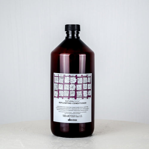 Bottle of conditioner on a white surface with a light gray background