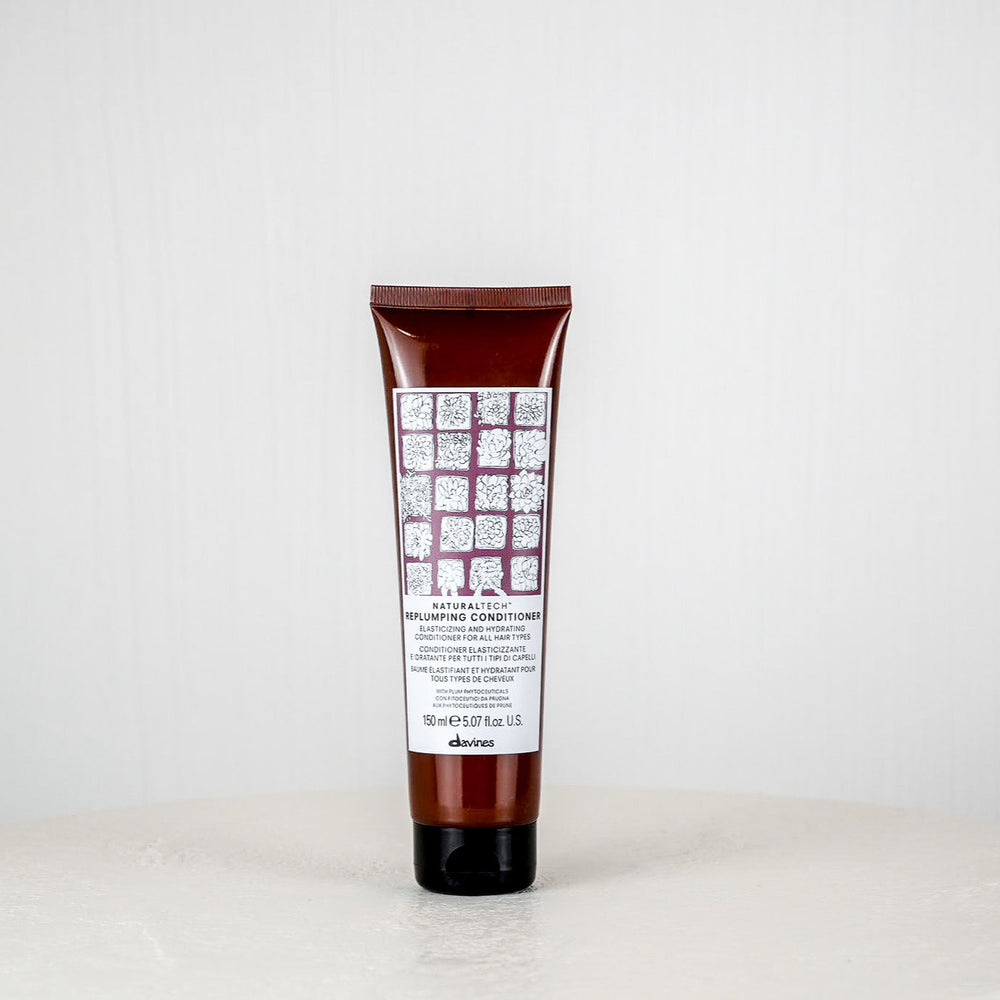 Tube of shampoo or conditioner with a white label on a white surface and light gray background