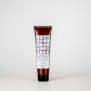 Tube of shampoo or conditioner with a white label on a white surface and light gray background