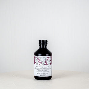 Bottle of Davines shampoo on a white surface with a white background
