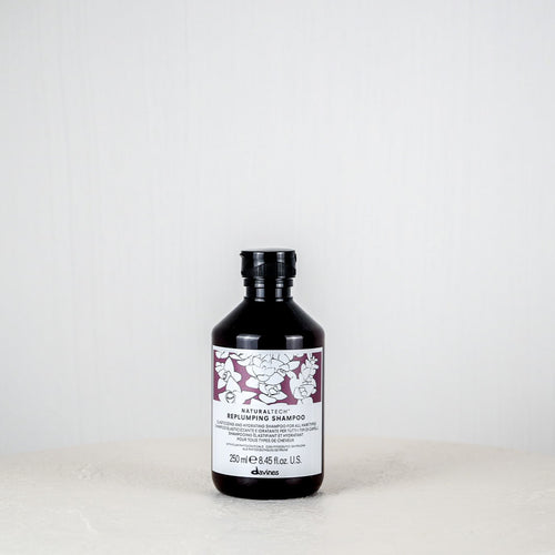 Bottle of Davines shampoo on a white surface with a white background