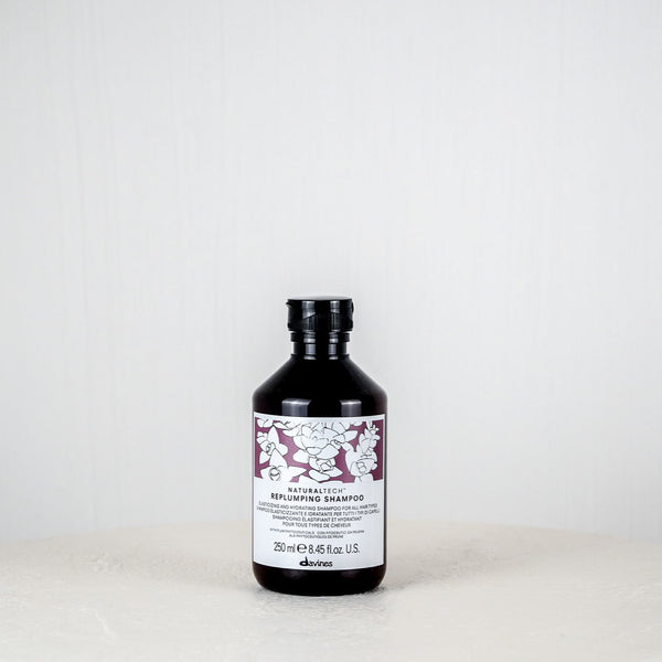 Bottle of Davines shampoo on a white surface with a white background