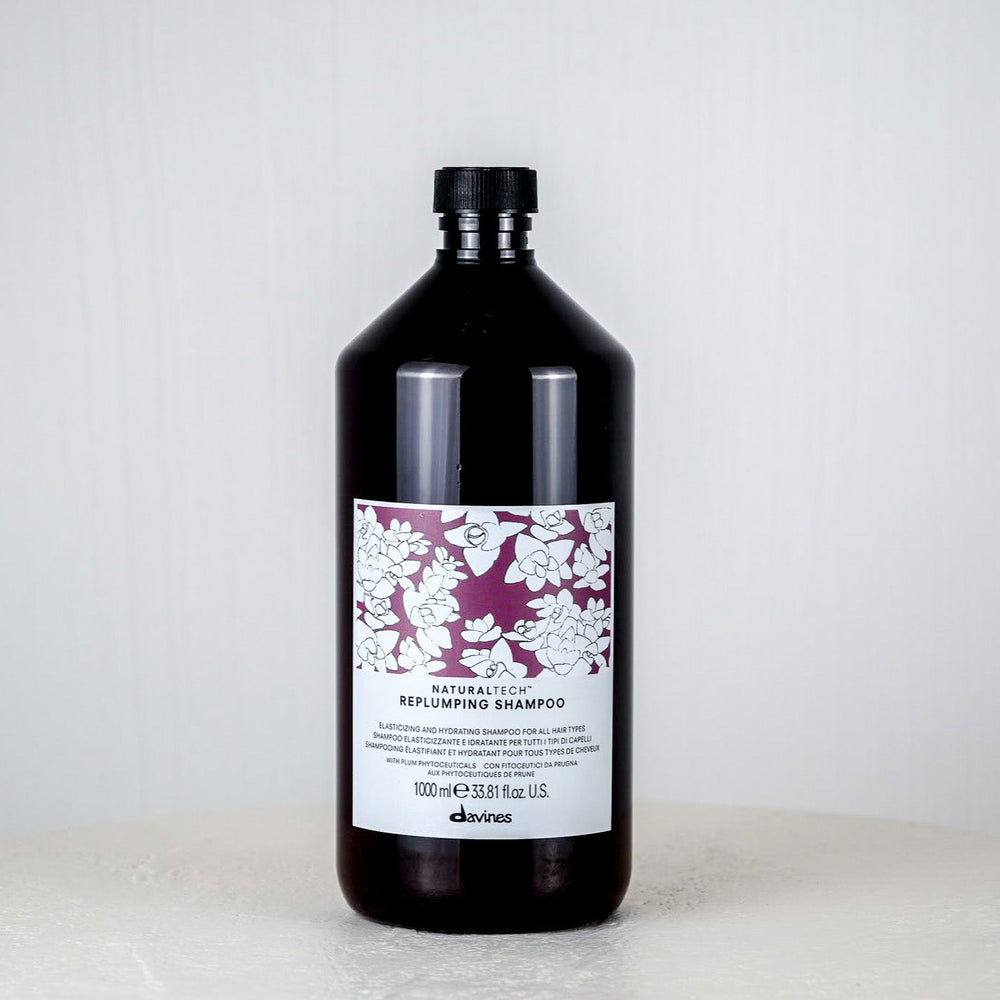 Bottle of Davines shampoo on a white surface with a white background