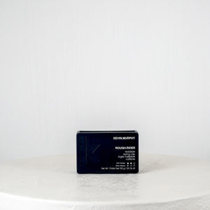Black rectangular product packaging on a white round surface with a light gray background