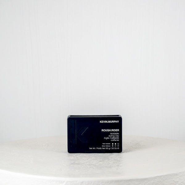 Black rectangular product packaging on a white round surface with a light gray background