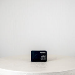 Black rectangular device on a white round table with a light gray background