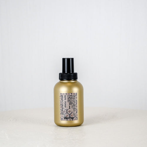 Gold spray bottle with black nozzle on a white background