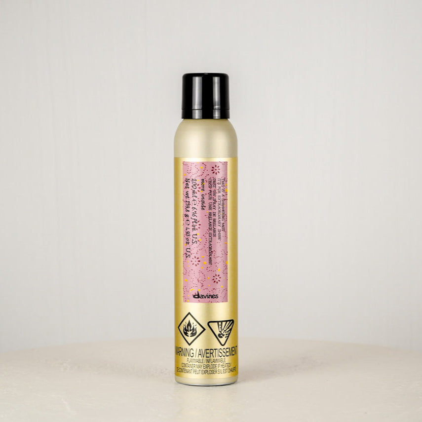 Hair spray bottle with a pink label on a light gray background