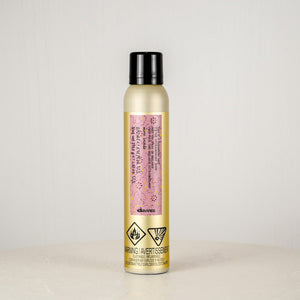 Hair spray bottle with a pink label on a light gray background