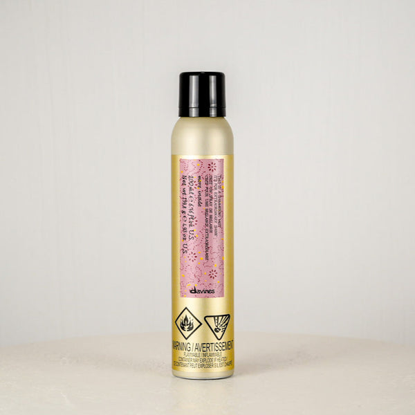 Hair spray bottle with a pink label on a light gray background