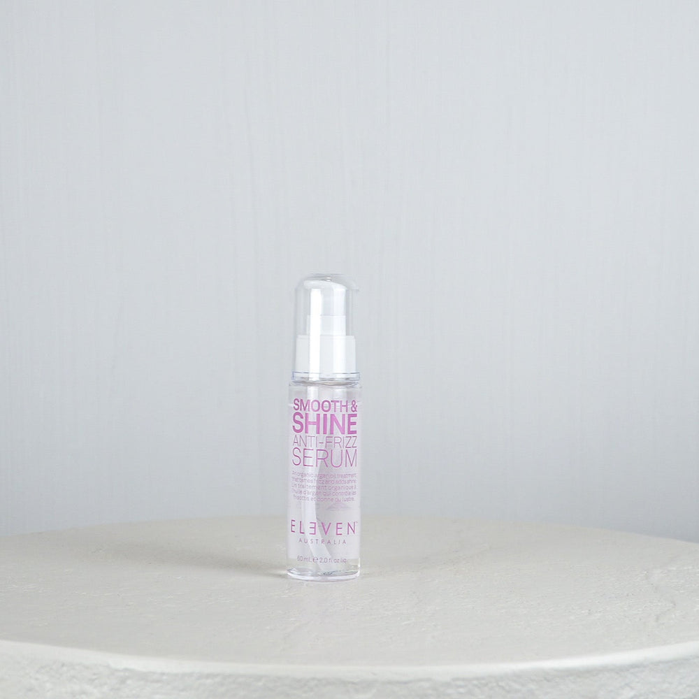 Bottle of 'Smooth & Shine Hair Serum' by 'Eleven' on a white surface with a light gray background