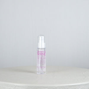 Bottle of 'Smooth & Shine Hair Serum' by 'Eleven' on a white surface with a light gray background