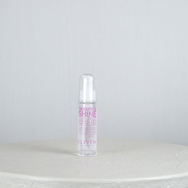 Bottle of 'Smooth & Shine Hair Serum' by 'Eleven' on a white surface with a light gray background