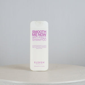 Shampoo bottle labeled 'Smooth Me Now Anti-Frizz Shampoo' by 'Eleven' on a gray background