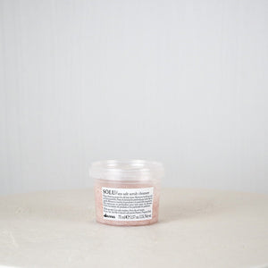 Jar of cream on a white surface with a light gray background