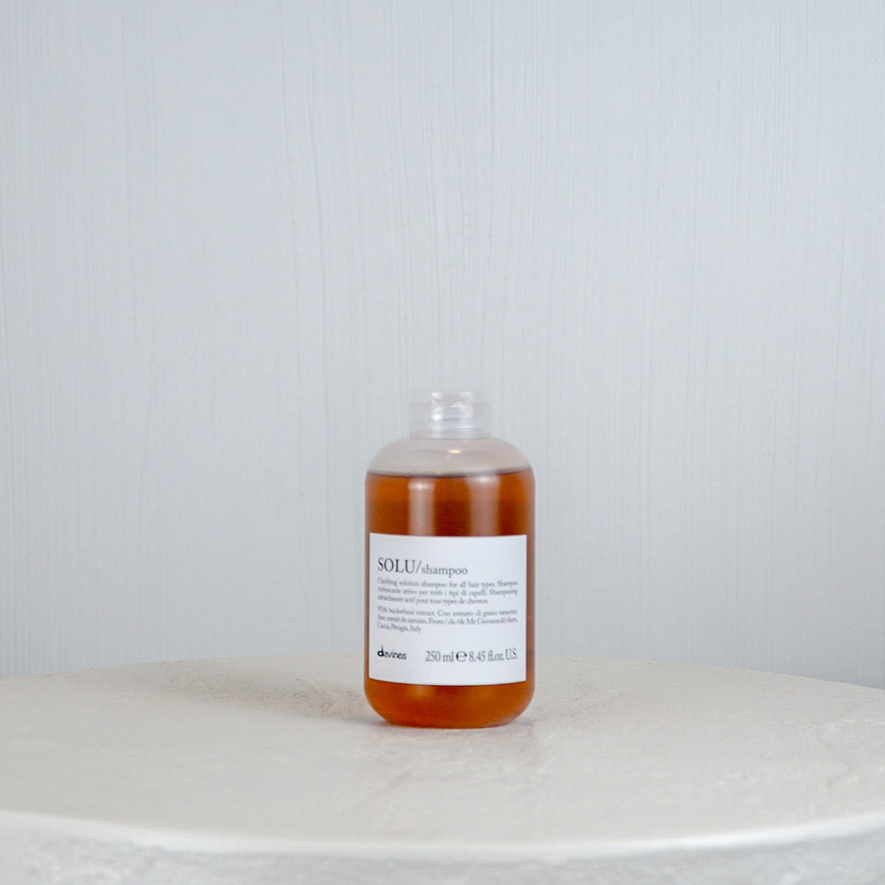 Bottle of liquid on a round marble surface with a light gray background