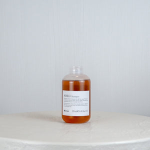 Bottle of liquid on a round marble surface with a light gray background