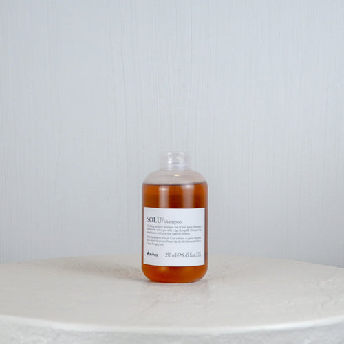 Bottle of liquid on a round marble surface with a light gray background