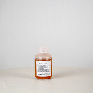 Bottle of shampoo on a white surface with a light gray background