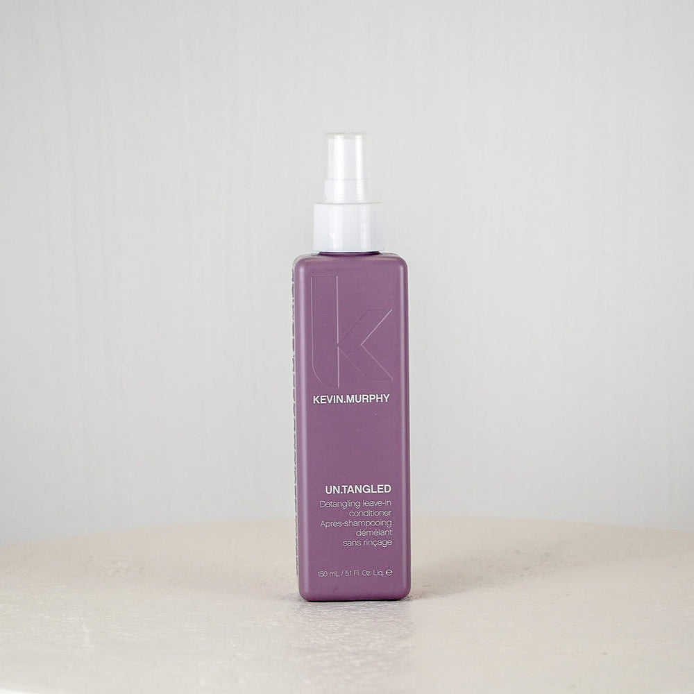 Purple bottle of Kevin Murphy hair product on a white surface with a white background