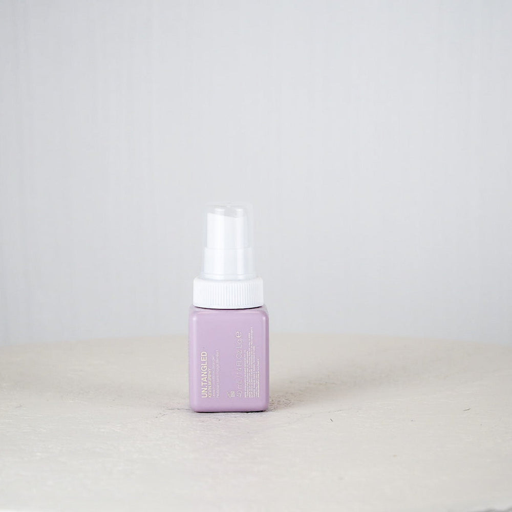 Purple bottle of Kevin Murphy hair product on a white surface with a white background
