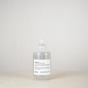Bottle of Davines hair product on a white surface with a plain background