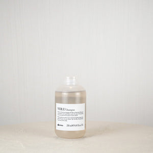 Bottle of Davines shampoo on a white surface with a white background