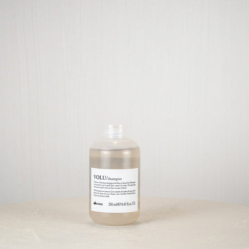 Bottle of Davines shampoo on a white surface with a white background