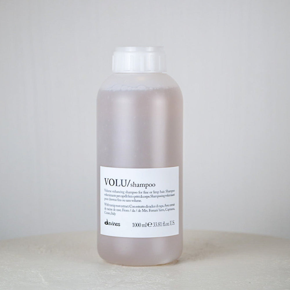 Bottle of Davines shampoo on a white surface with a white background