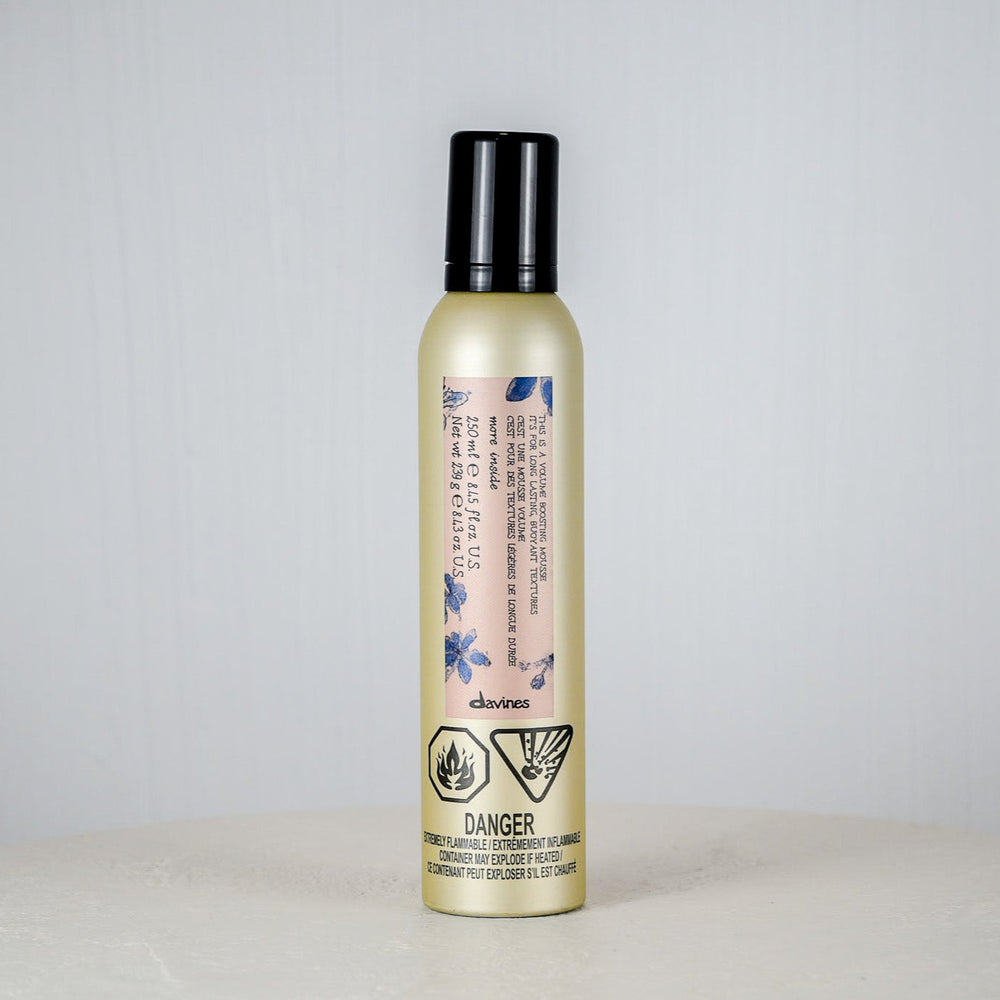 Bottle of hair product on a white surface with a light gray background