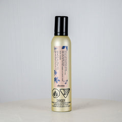 Bottle of hair product on a white surface with a light gray background