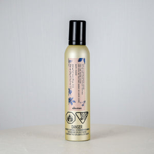 Bottle of hair product on a white surface with a light gray background