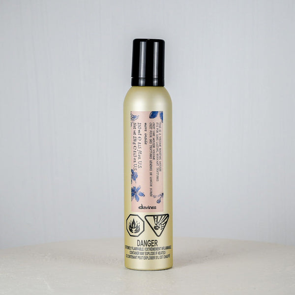 Bottle of hair product on a white surface with a light gray background