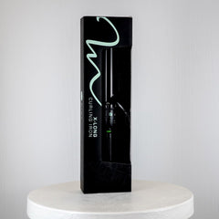 Black hair styling tool packaging on a white pedestal with a light gray background