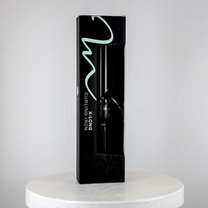 Black packaging of a curling iron on a white platform with a light gray background